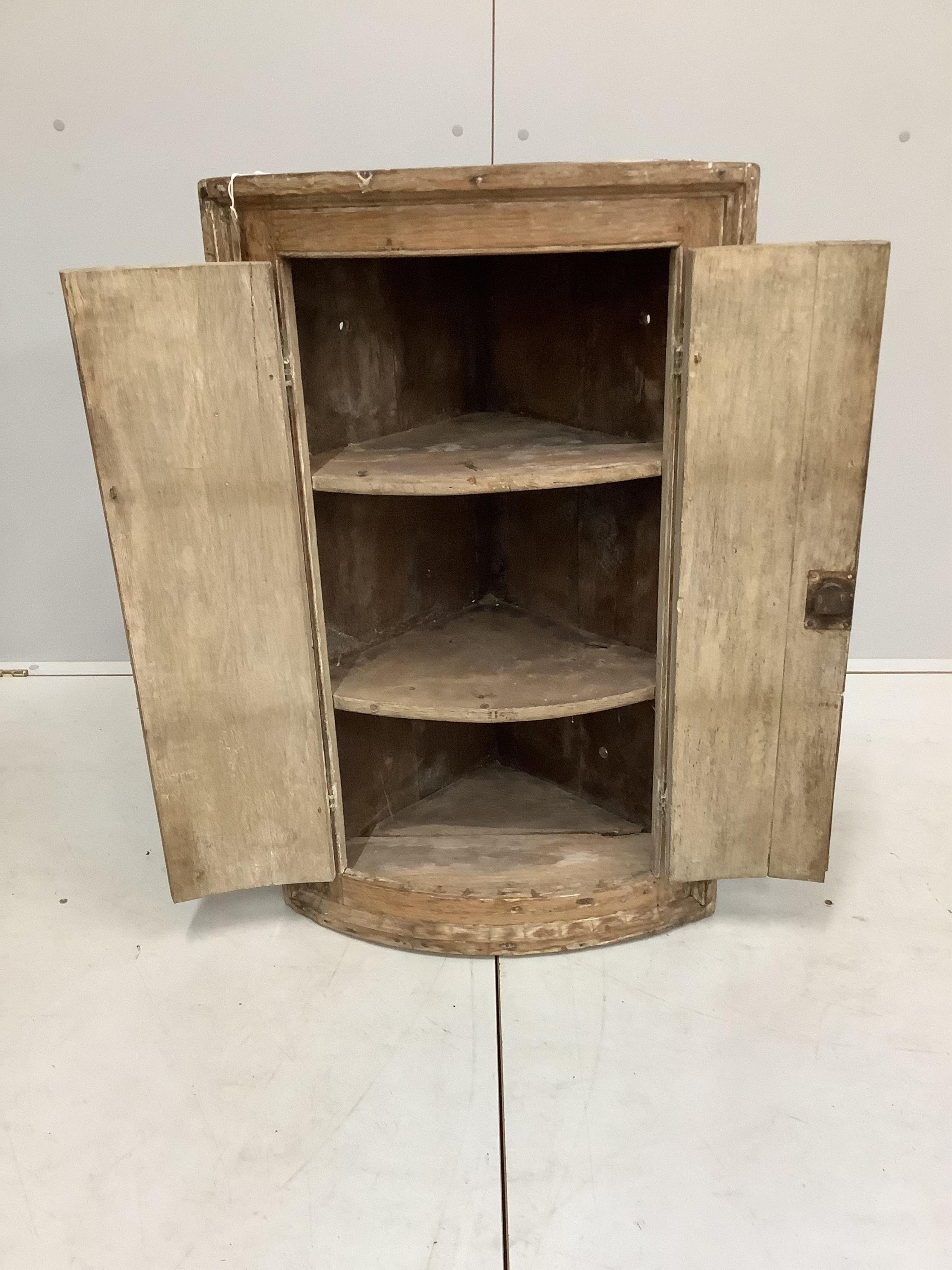 An 18th century oak bow front hanging corner cupboard, width 56cm, depth 38cm, height 91cm